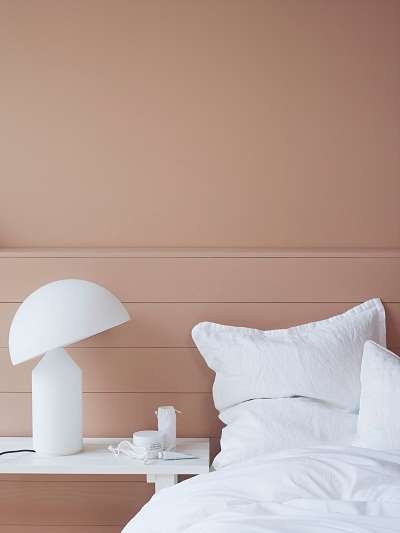 Pudderfarget vegg mot hvitt sengetøy